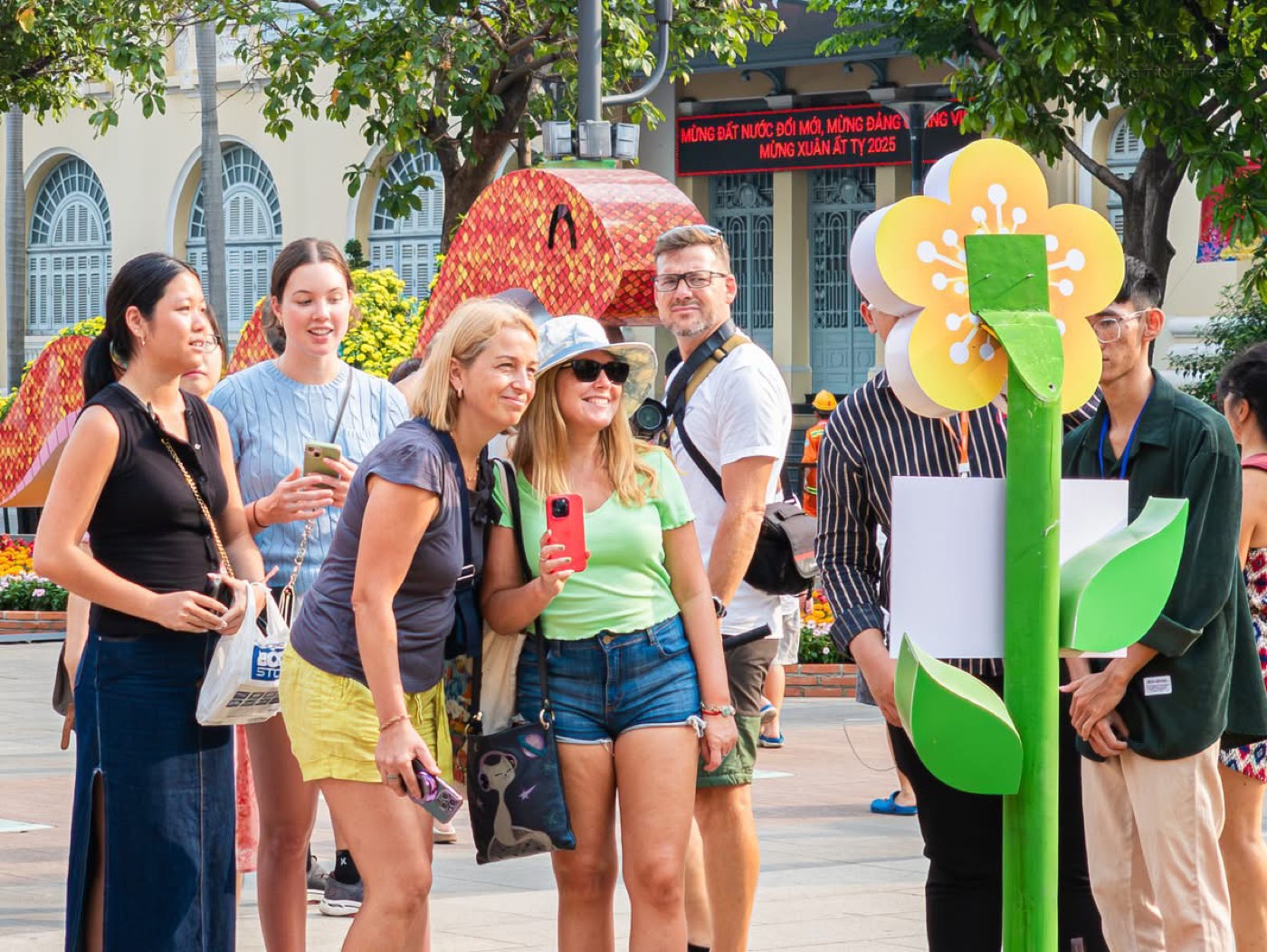 Visitors taking a selfie beside the robot's flower sign
